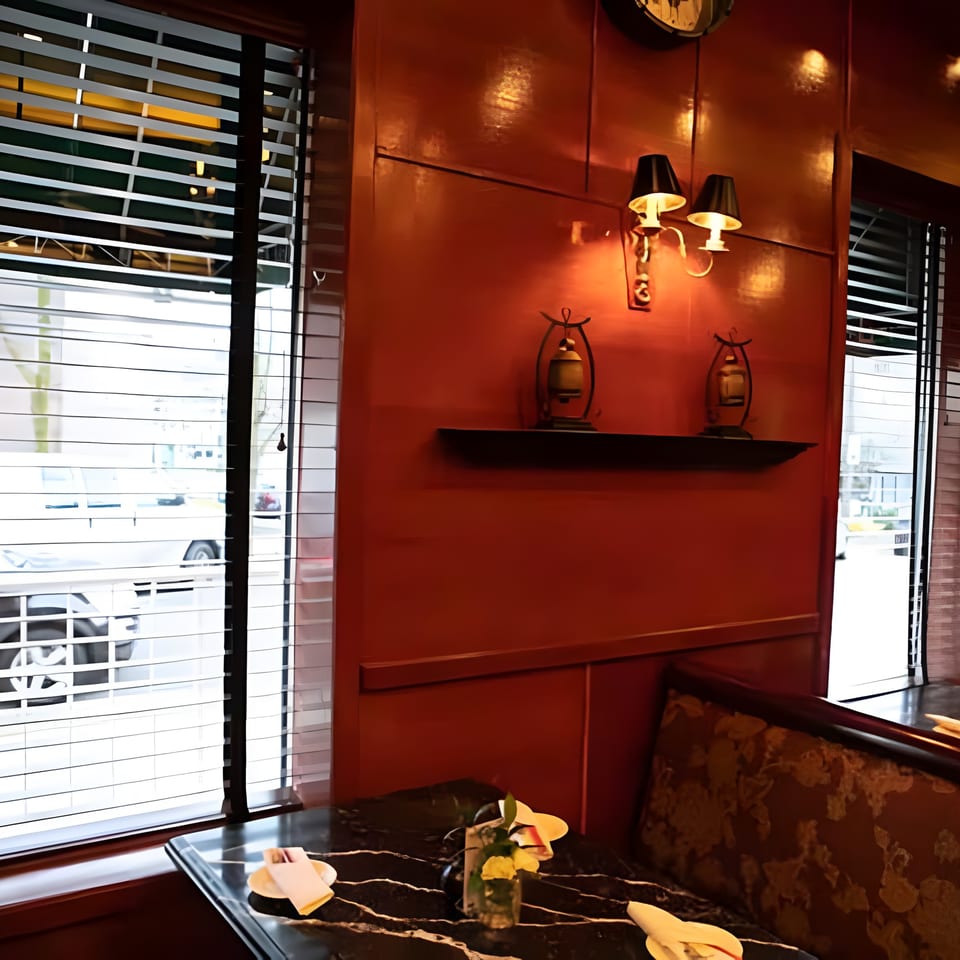 Cozy Asiana Cafe interior with a dark marble table, patterned booth, and warm lighting on a red wall.