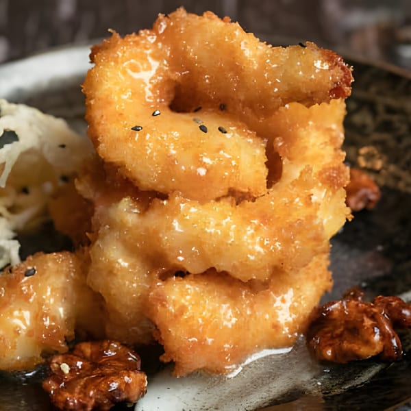 Asiana Cafe's honey walnut shrimp, golden-fried and glazed, served with candied walnuts on a dark plate.