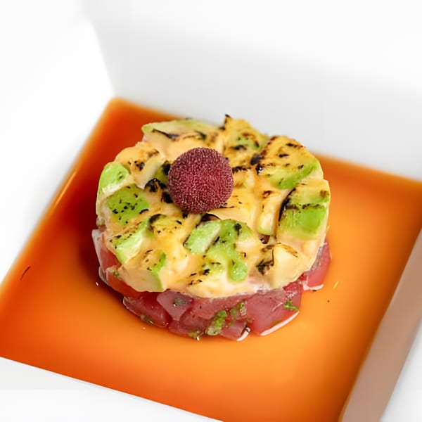 Asiana Cafe's tuna tartare with avocado, sauce, and a red berry on an orange plate.