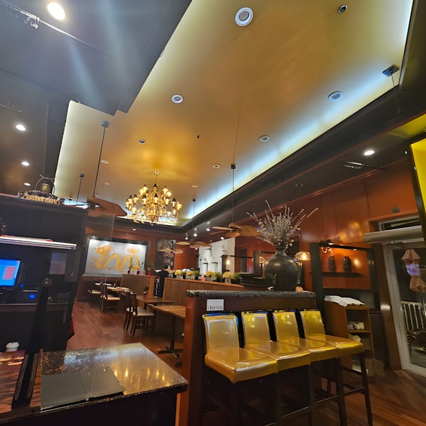 Interior of Asiana Cafe, featuring a chandelier, golden dragon art, and bar seating with yellow chairs.
